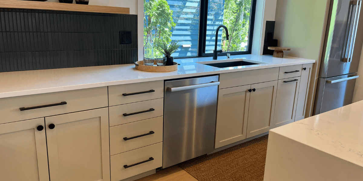 White shaker base cabinets beside a dishwasher and dark countertop