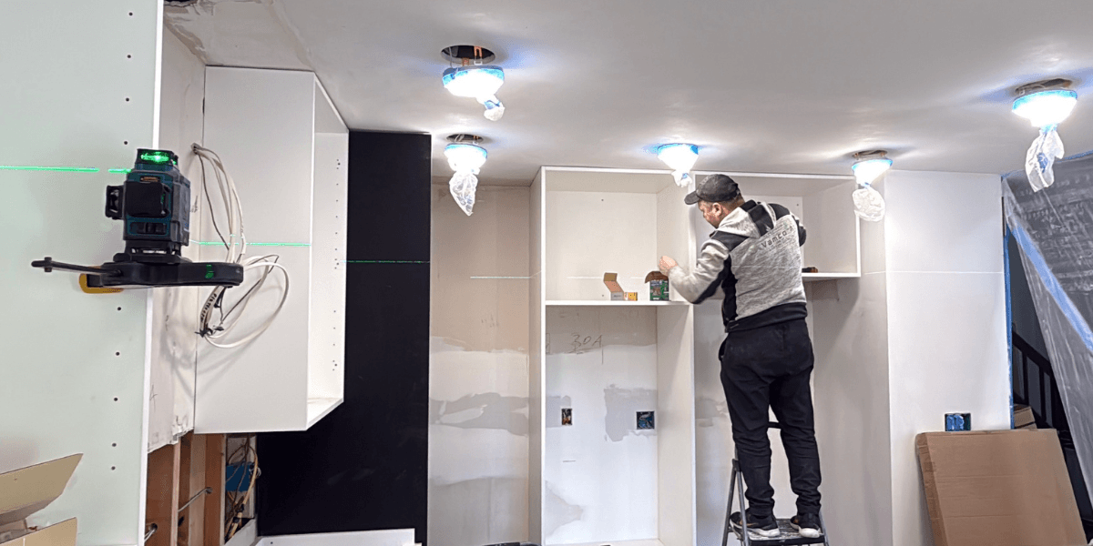 Installer fitting white kitchen cabinets during a remodel