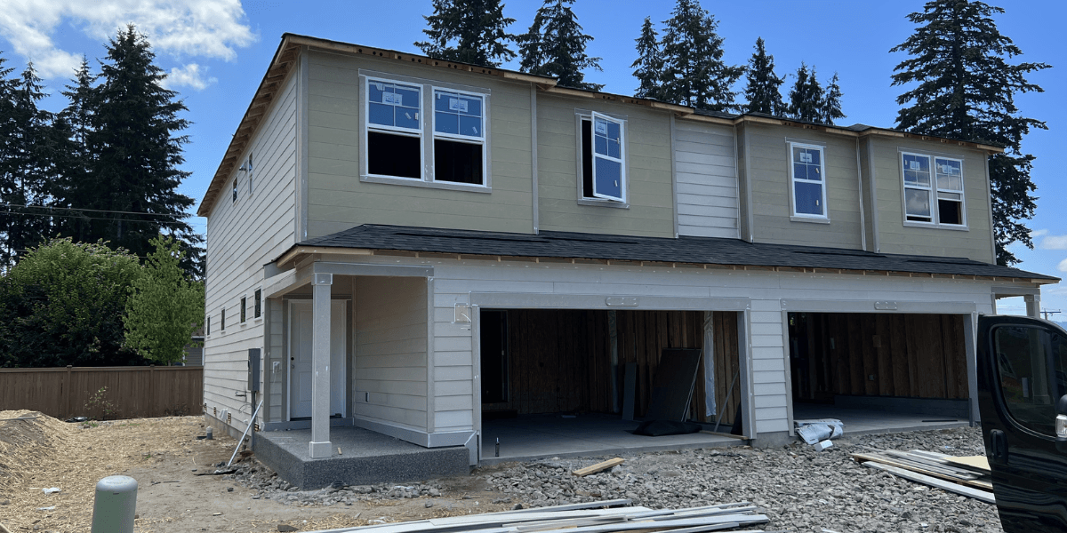 Two-story home during light-colored siding installation