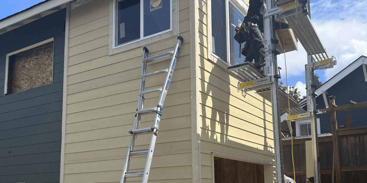 Installer working from a ladder on lap siding and window trim