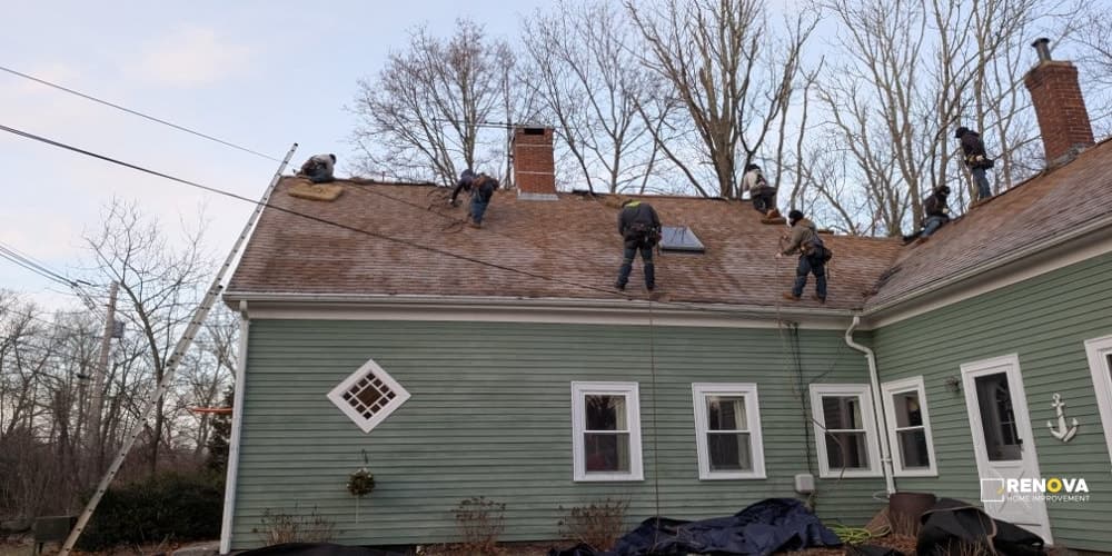 Roofing crew removing shingles from a residential roof